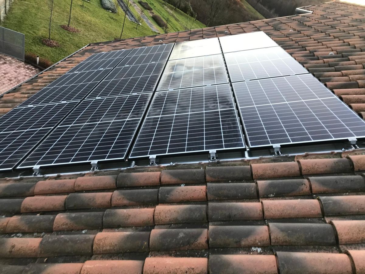 Dettaglio dei moduli fotovoltaici neri installati, cielo riflesso